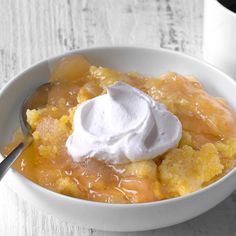 a white bowl filled with fruit and topped with whipped cream