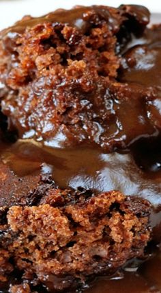 two chocolate desserts on a white plate covered in melted chocolate and drizzled with icing