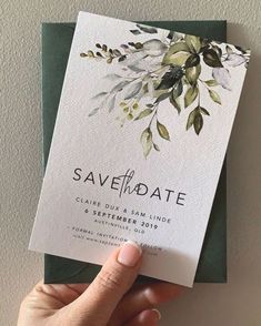 a person holding up a card that says save the date with leaves and branches on it