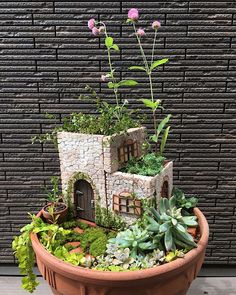 a potted planter filled with plants and a small house on top of it