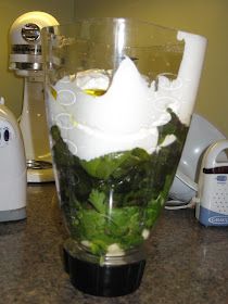 a blender filled with green leafy vegetables on top of a granite countertop