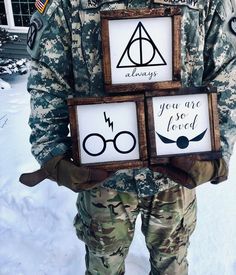 a man in camouflage holding two framed harry potter signs