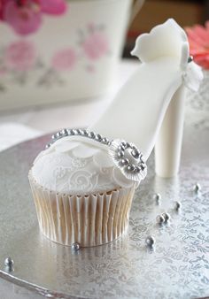 a cupcake that is sitting next to a pair of high heel shoes on a table