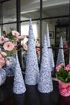 several blue and white vases with flowers in them on a table next to a mirror