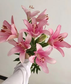 a white vase filled with pink flowers on top of a table