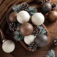 some balls and pine cones are sitting on a wooden table with other ornaments around them