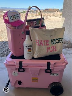 a pink cooler filled with lots of items and a tote bag sitting on top of it