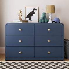 a blue dresser with some stuffed animals on top and a lamp next to it in a room