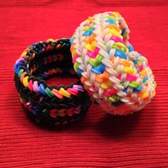 two colorful bracelets sitting on top of a red surface