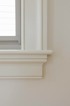 the corner of a window sill is shown with a white frame and molding