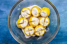 a glass bowl filled with lemons covered in powdered sugar on top of a blue table