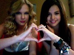 two beautiful young women making a heart shape with their hands