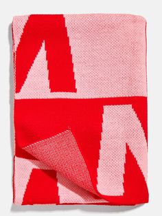 a red and white knitted blanket with an arrow pattern on the front, folded in half