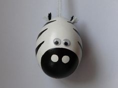 a ceramic zebra ornament hanging from a string on a white wall with black and white stripes