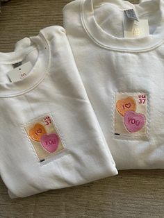 two white tshirts with heart patches on them