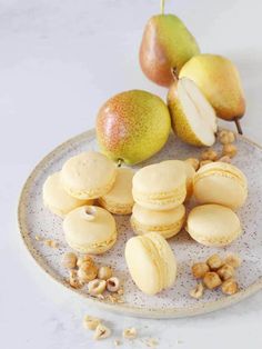 macaroons, pears and walnuts are on a plate with white background