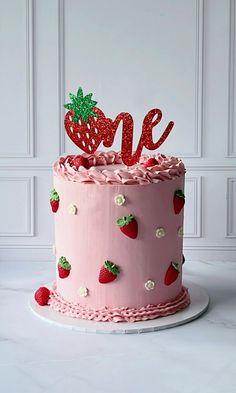 a pink cake decorated with strawberries and the word me