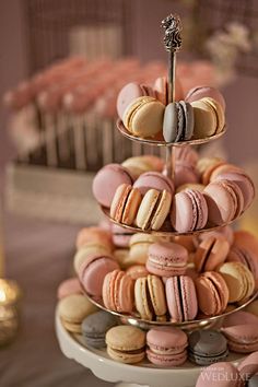 three tiered trays filled with macaroons on top of a cake table