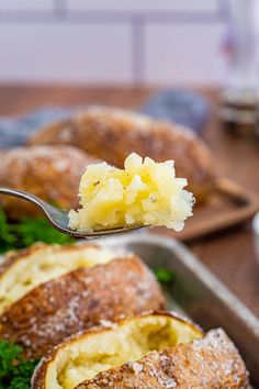 a spoon with some food in it on top of a pan filled with bread and vegetables