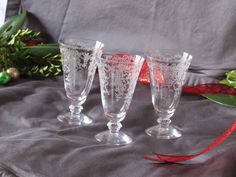 three wine glasses sitting on top of a table next to a red ribbon and christmas decorations