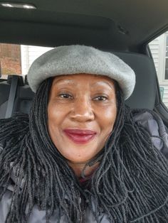 a woman in a car wearing a hat and scarf