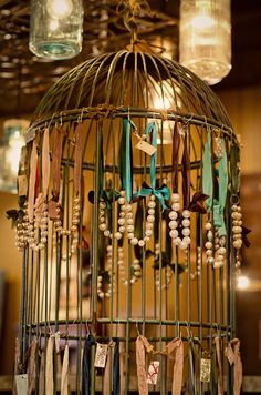 a birdcage filled with lots of beads and ribbons hanging from it's sides