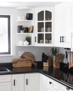 a kitchen with white cabinets and black counter tops is pictured in this image, there are wooden utensils on the counter