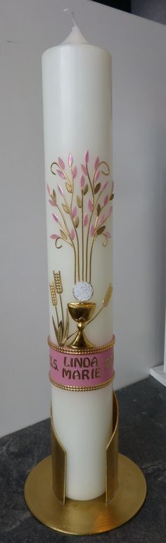 a white candle with pink and gold designs on it