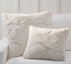 two pillows sitting on top of a white couch