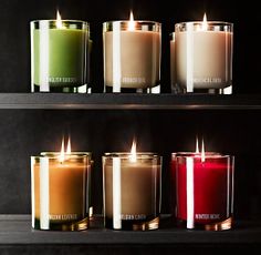 four candles are lined up next to each other in different colors and sizes, with the candle lit