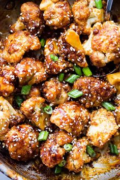 a pan filled with chicken and vegetables covered in sesame seeds