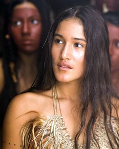 a woman with long hair wearing a feathered top and looking off to the side