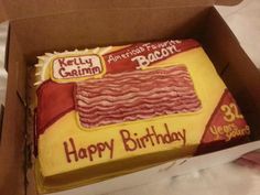 a birthday cake in a box with bacon on it