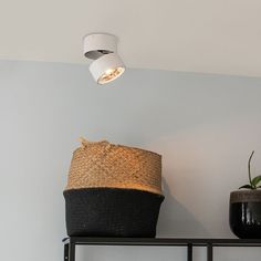 a basket sitting on top of a metal shelf next to a lamp and potted plant