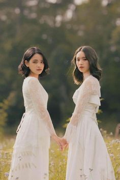 two young women in white dresses holding hands