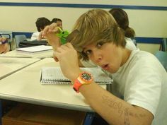 a young boy sitting at a desk with an apple watch on his hand and writing on the paper