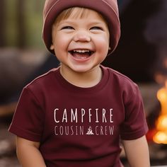 Join the "Campfire Cousin Crew" with our trendy graphic tee!  This comfy tee celebrates the bond only cousins can share in and around the bonfire. Think marshmallows, fireflies and hunting for that bullfrog amidst a campfire glow. Crafted for comfort and durability, the "Campfire Cousin Crew" shirt is a must-have for every camping, cottage or family adventure in the great outdoors. This unisex youth short sleeve tee is lightweight and side-seamed for comfort all day long.  Made with extra lightw Red Short Sleeve T-shirt For Outdoor, Red Short Sleeve T-shirt For Outdoors, Custom Print Crew Neck T-shirt For Camping, Graphic Tee With Text Print For Camping, Fun Short Sleeve Tops For Outdoor Activities, Cotton T-shirt With Text Print For Camping, Red Cotton Tops For Outdoor Activities, Family Matching Outdoor T-shirt With Letter Print, Family Matching Outdoor Letter Print T-shirt