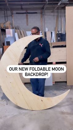 a man standing in front of a wooden moon with the words our new foldable moon back drop