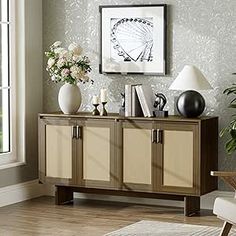 a living room with a chair, table and vases on the sideboard in front of a window