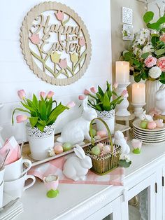 a white table topped with lots of vases filled with flowers and plants on top of it