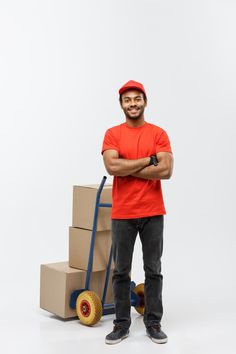 a man in an orange shirt is standing next to boxes and a hand truck with wheels