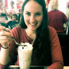 a woman sitting at a table with a milkshake and ice cream in front of her