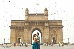 a man and woman standing in front of an arch