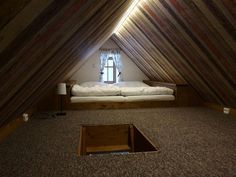 an attic bedroom with a bed in the middle and a window on the other side