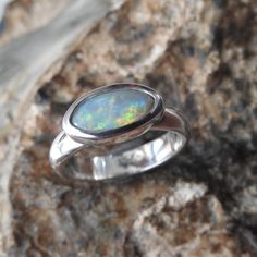 LIGHTNING RIDGE SOLID OPAL RING Opal Type : Australian Solid Light Opal Carat Weight : 1.05 ct Size : 5.30 mm x 11.00 mm approx. Color : Green Blue Orange Shape : Marquise Cut : Low Dome Cabochon Clarity : Opaque Brightness B1 - B5 : B3.5 B1:Faint  B2:Dull  B3:Bright  B4:Very  Bright B5:Brilliant Body Tone N1-N9 : N7 Light Opal N1-N4:Black  Opal N5-N6:Dark  Opal N7-N9:Light Opal Treatment : NONE Origin : Lightning Ridge Opal Field, NSW Australia. ------------------------------------------------- Solid Opal Ring, Australian Opal Ring, Lightning Ridge Opal, Ring Opal, Nsw Australia, Lightning Ridge, Toned Body, Australian Opal, Opal Ring