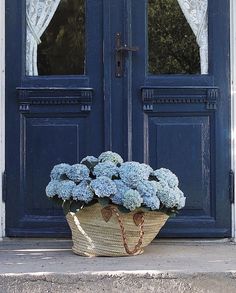 a basket full of blue flowers sitting in front of a door