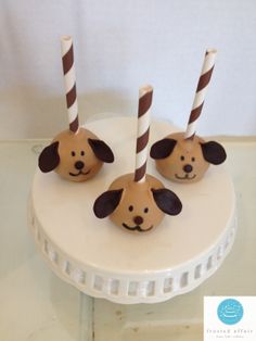 three brown and white dogs with striped straws on top of a cake platter