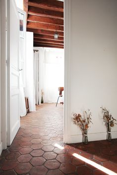 an open door leading into a room with white walls and red tile flooring on either side