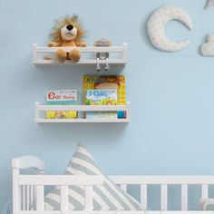 a baby's room with blue walls and white crib, bookshelves and toys