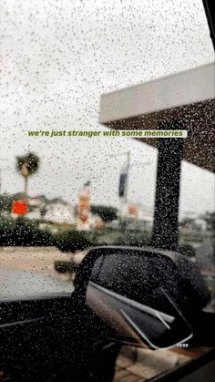 rain is falling down on the windshield of a car in front of a gas station